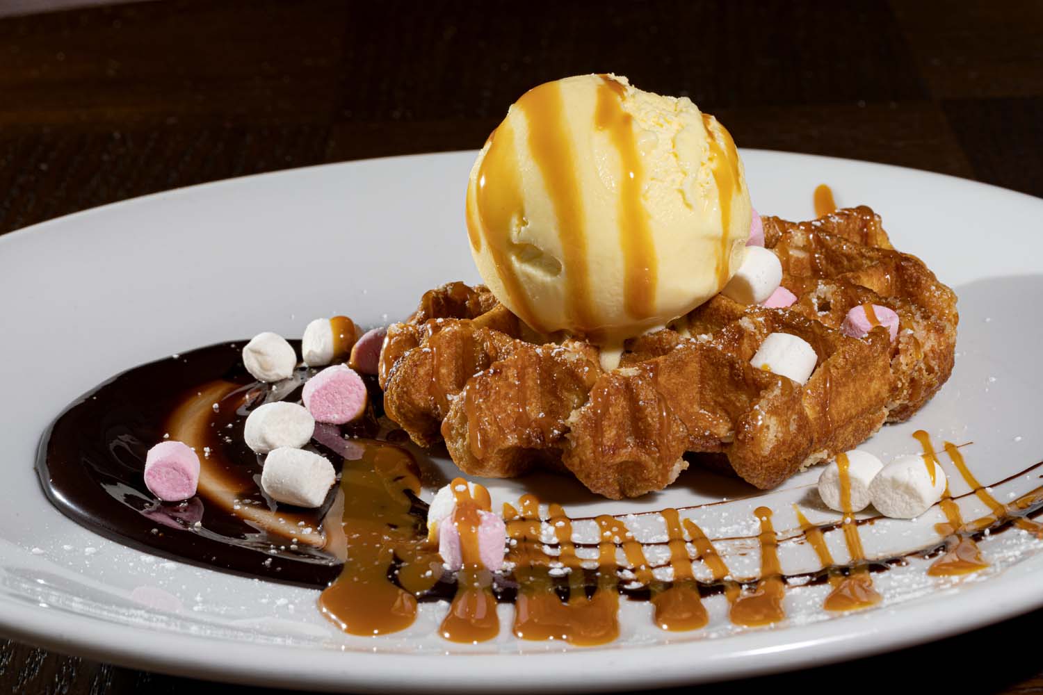 Belgian waffle with white and milk chocolate sauce with marshmallows and ice cream