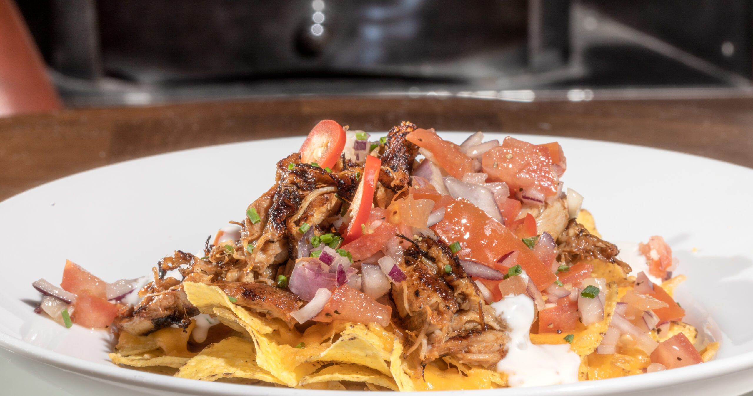 Pulled pork nachos smothered in smoky BBQ sauce, garlic aioli melted cheddar and topped with Pico de Gallo