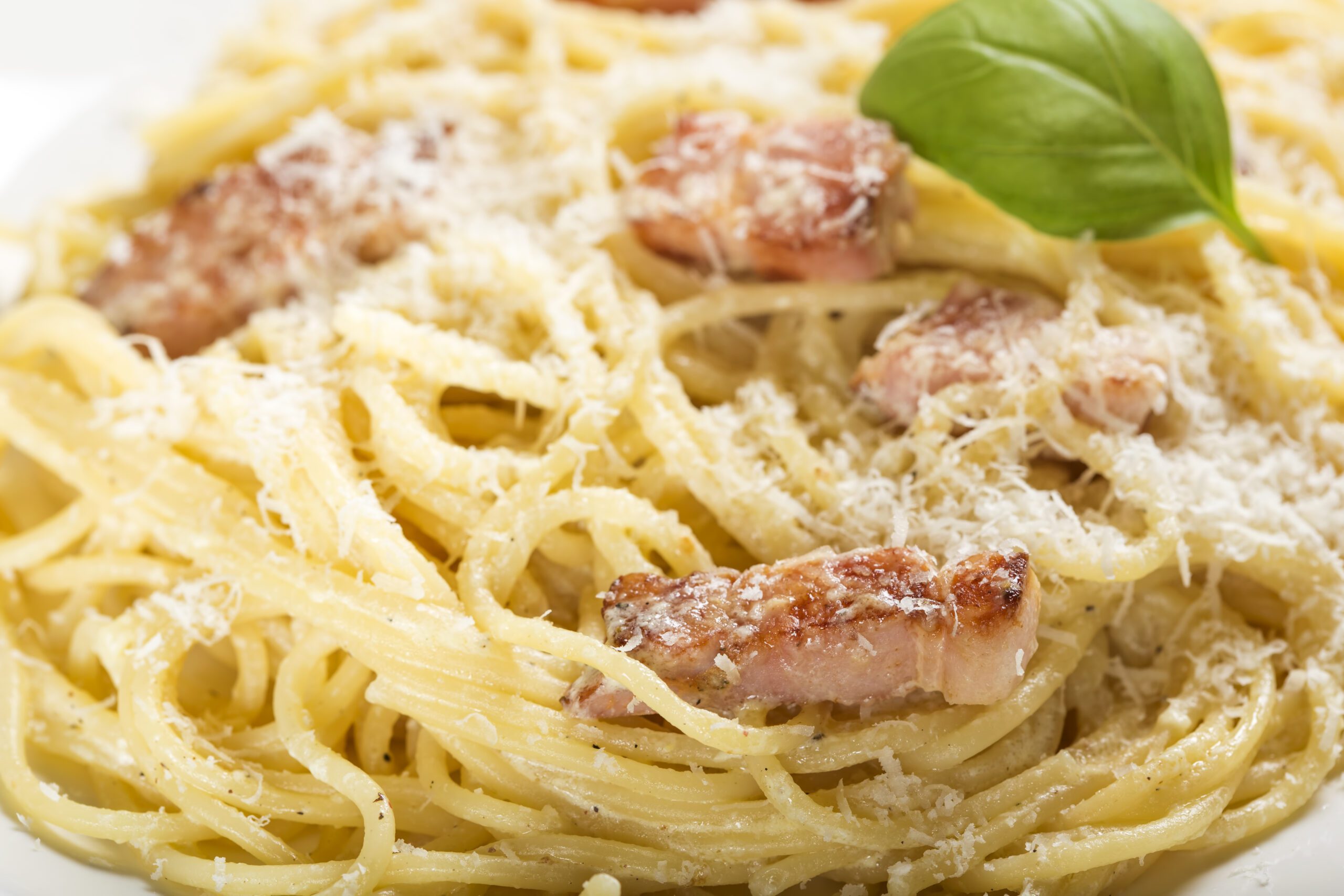 Plate with traditional Italian pasta Carbonara with grated Parmesan and basil